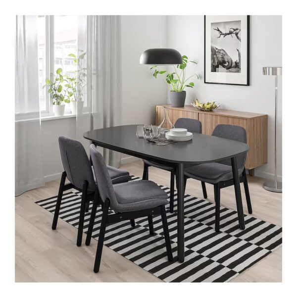 A contemporary dining room with a black oval table, gray upholstered chairs, a credenza, and a wall art piece.